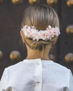 Peinado recogido bajo con flores rosadas - Peinados primera comunión